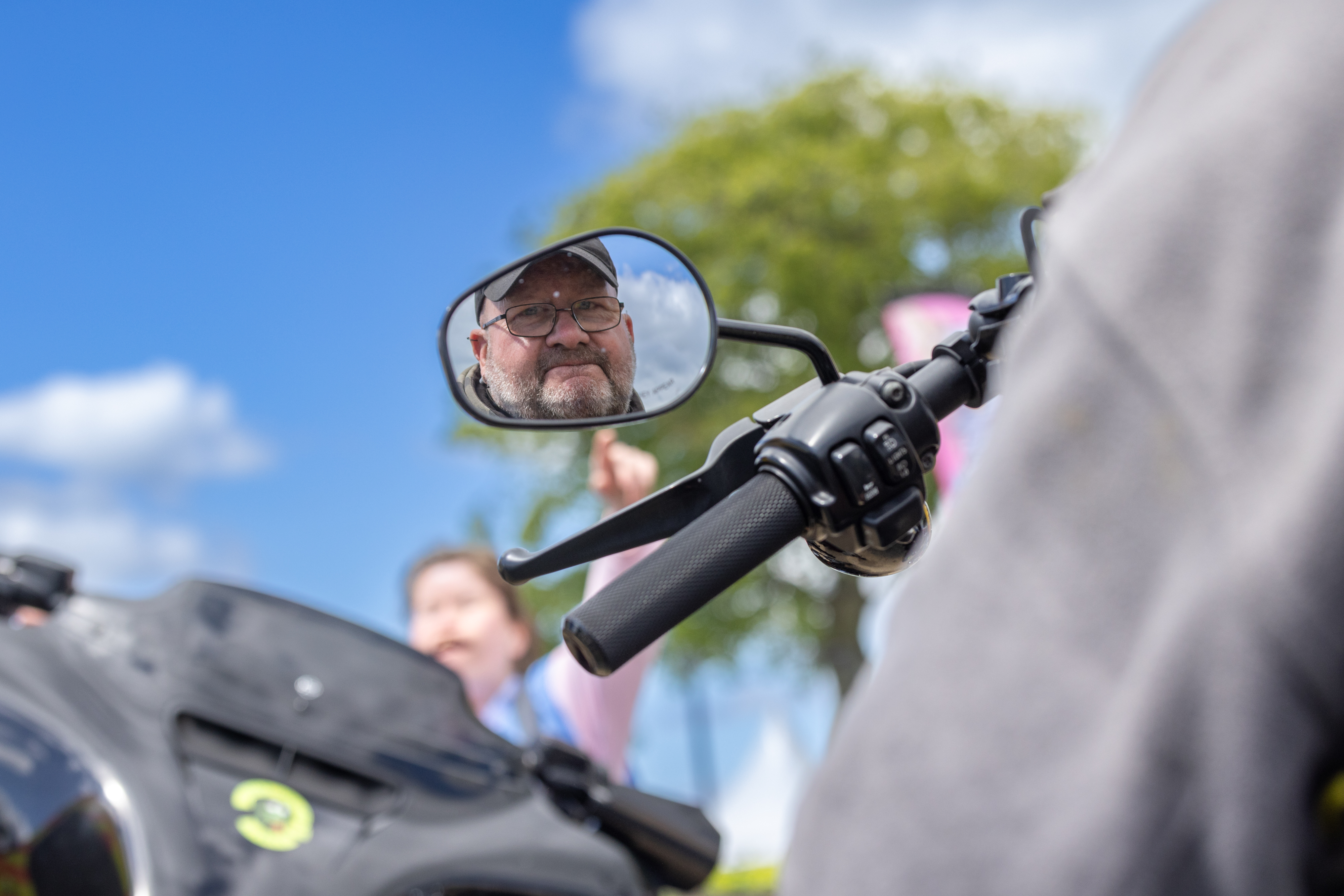 Reflection of Person smiling in motorbike mirror. 